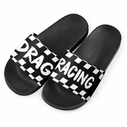 A pair of black slide sandals with a wide strap featuring a black and white checkered pattern and the words 'DRAG RACING' in white.