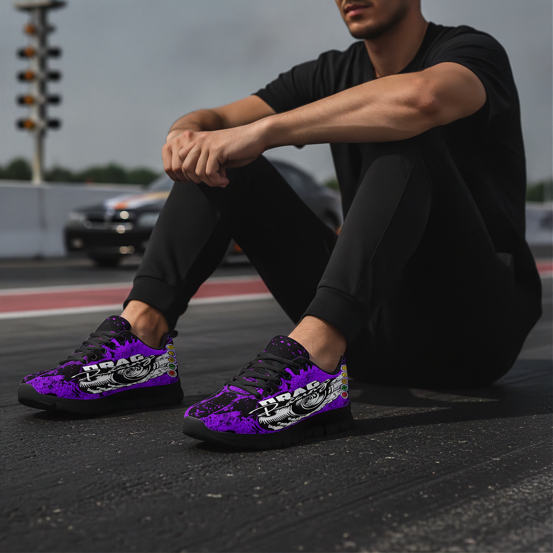 Person wearing purple and black sneakers with a logo, sitting on a track.