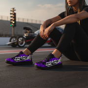 Person wearing purple sneakers with 'Drag' design sitting on a street with a car in the background.