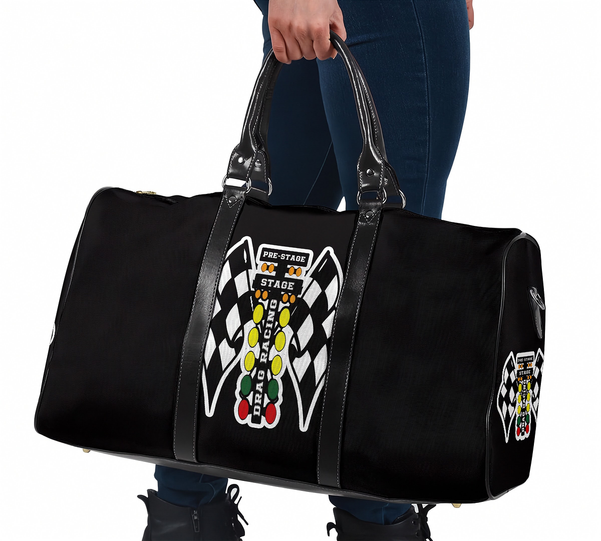 A black duffel bag with racing-themed graphics, held by a person wearing blue jeans and black boots against a white background.