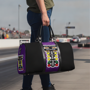 A person standing on a racetrack holds a black duffel bag with purple side panels and a large racing-style graphic reading 'PRE-STAGE', 'STAGE', and 'DRAG RACING'.
