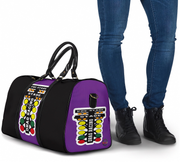A purple and black duffel bag with a bold graphic print featuring the words 'FUEL STATION' and colorful circular icons, shown next to a person wearing blue jeans and black boots on a white background.
