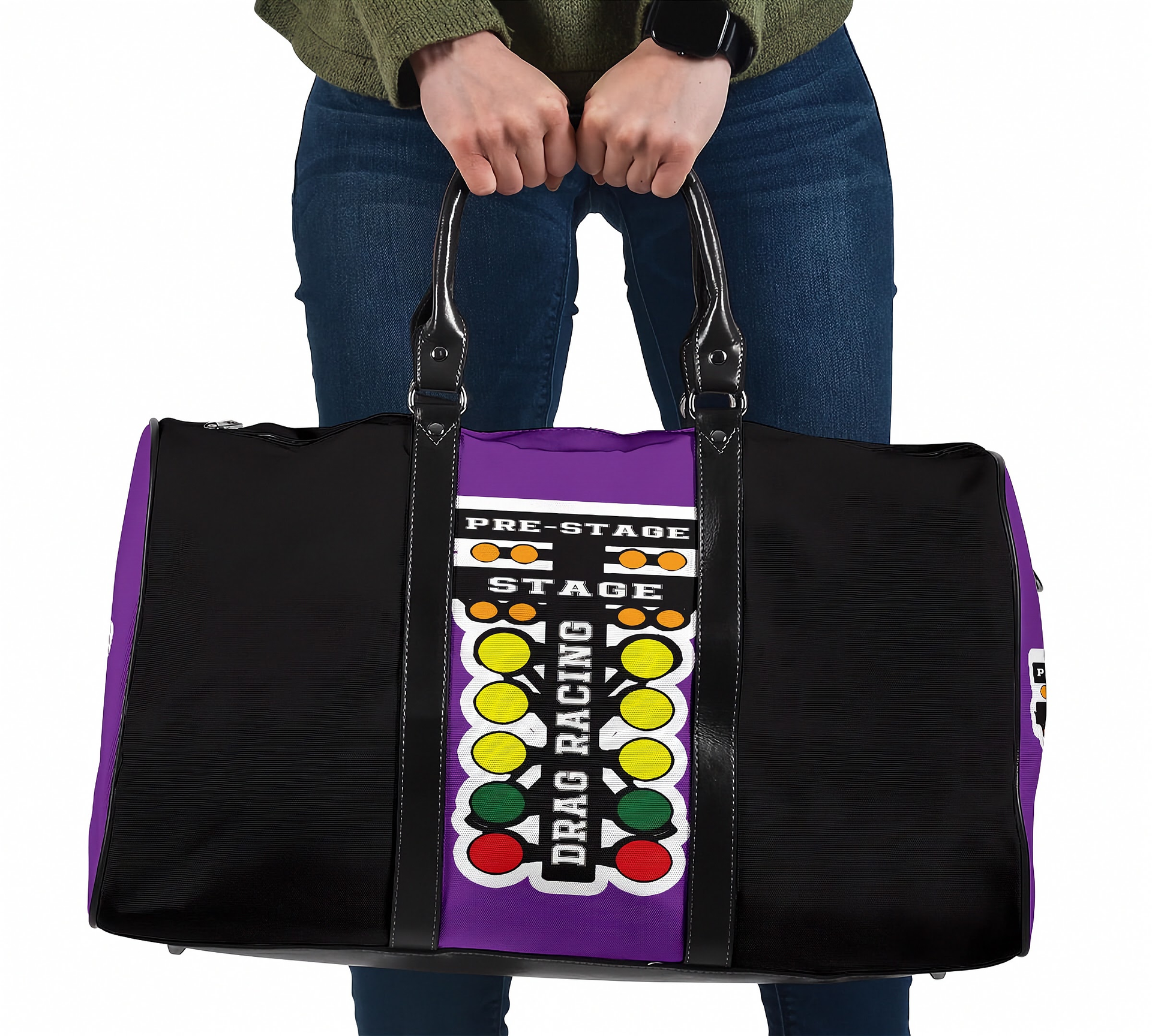 A person holding a black and purple duffel bag with a drag racing theme, featuring a vertical graphic with the words 'PRE-STAGE', 'STAGE', and 'DRAG RACING' alongside colorful light bulbs.