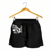 Black athletic shorts with a white 'Drag Racing' tire graphic and a vertical row of red, yellow, green, and white traffic light-style dots on the left side, hanging from a wooden hanger against a white background.