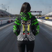 A person standing on a drag strip wearing a black hoodie with a green splatter pattern and a large drag race light graphic on the back, shown from behind.