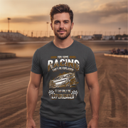 Man wearing a t-shirt with racing graphic and text at a race track.