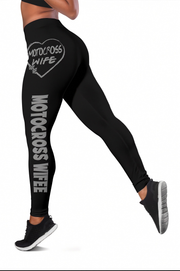 Black high-waisted athletic leggings with 'MOTOCROSS WIFE' printed in white on the upper thigh and down one leg, shown on a model from the waist down against a white background.