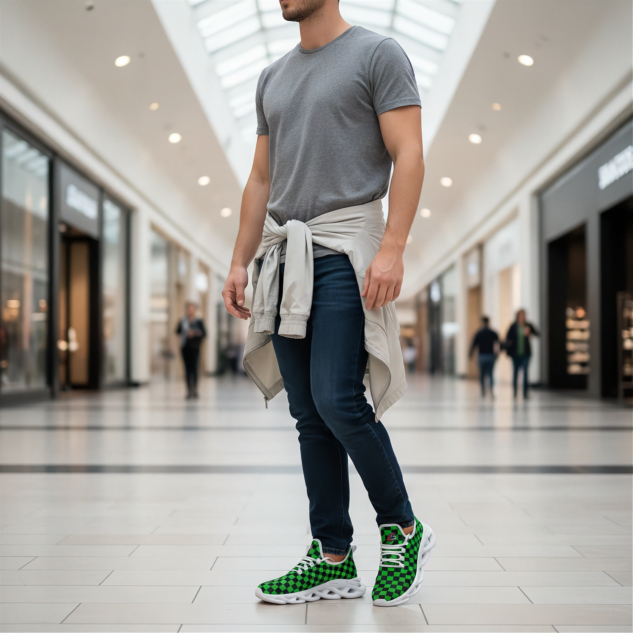 Man wearing a gray t-shirt, dark jeans, and green checkered sneakers in a mall.
