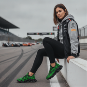 Woman sitting on a race track wearing green and black checkered sneakers.