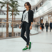 Woman in a mall wearing a black jacket, white t-shirt, black jeans, and green checkered sneakers.