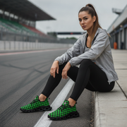 Woman sitting on a race track wearing green and black checkered sneakers.