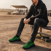 Man sitting on a bench at a race track wearing green and black checkered shoes.