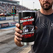 A man in a gray t-shirt holds up a black insulated tumbler with a clear lid. The tumbler features a graphic of a drag racing car and the text 'I HAVE A DRAG RACING PROBLEM, ALSO HAVE NO INTENTION OF FIXING IT' in white and red.