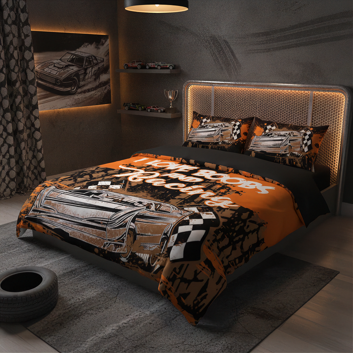 A racing-themed bedding set displayed on a bed in a modern, dark-themed bedroom. The set features an orange and black duvet cover with a graphic of a race car and the text 'I LOVE BOOBS AND RACING', matching patterned pillowcases, and a black and orange striped patterned sheet.