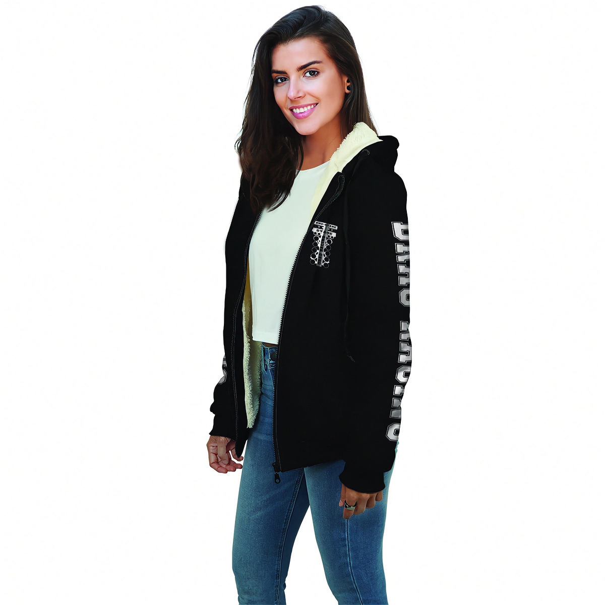A woman modeling a black zip-up hoodie with a light beige fleece lining. The hoodie features a white graphic print on the left chest and white text down the right sleeve.