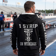 a man standing at a drag race track wearing a black sherpa jacket with text "I STRIP ON WEEKENDS"