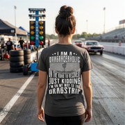 Woman wearing a t-shirt with a humorous drag racing graphic and text at a race track.