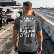 Woman wearing a gray t-shirt with drag racing-themed text at a race track.