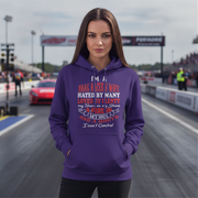 A woman stands on a drag racing track wearing a purple hoodie with a graphic text print on the front. The text reads: 'I'M A DRAG RACE WIFE HATED BY MANY LOVED BY MANY my heart is in a race AFIRE IN MY SOUL I can't Control'.
