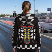 A woman stands on a drag racing track wearing a black hoodie with a large drag racing graphic on the back and 'I'M NOT ALL GIRLS' printed down the sleeves. The background shows the racetrack, grandstands, and sky.