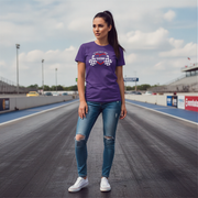 Woman wearing a purple t-shirt and blue jeans standing on a race track.