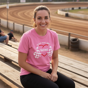 Woman wearing a pink t-shirt with racing design at a race track.