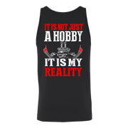A black sleeveless tank top with a bold graphic print on the front reading 'IT IS NOT JUST A HOBBY IT IS MY REALITY' in red and white text, featuring a skull and crossed tools graphic in the center.