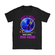 A black short-sleeve crewneck t-shirt featuring a colorful graphic print on the front. The design shows a blue full moon, a witch riding a broomstick, jack-o'-lanterns, tombstones, and the text 'JUST A WITCH WHO LOVES DRAG RACING' in pink and white.