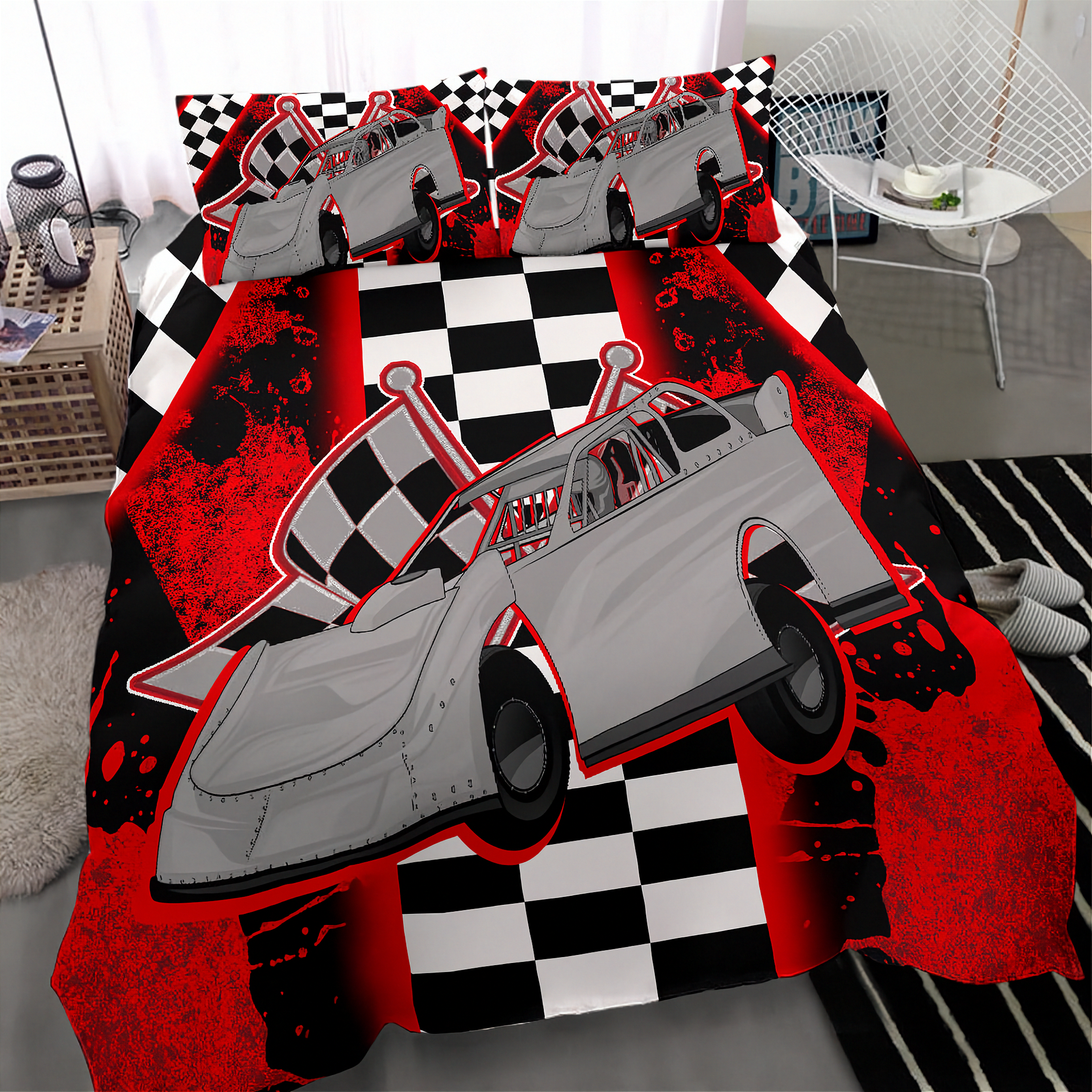 A racing-themed bedding set featuring a duvet cover and two pillowcases with a bold graphic print of a gray late model race car, red paint splatters, and a black-and-white checkered pattern, shown on a bed in a styled bedroom setting.
