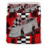 A racing-themed bedding set featuring a duvet cover and two matching pillowcases with a graphic print of a gray late model race car, checkered flags, and a black-and-white checkered pattern on a red splattered background.
