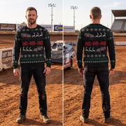 A man stands in a dirt racing track wearing a dark holiday sweater, shown from both the front and back. The sweater has a green base with white snowflakes, red 'HO-HO-HO' text, and white reindeer silhouettes.