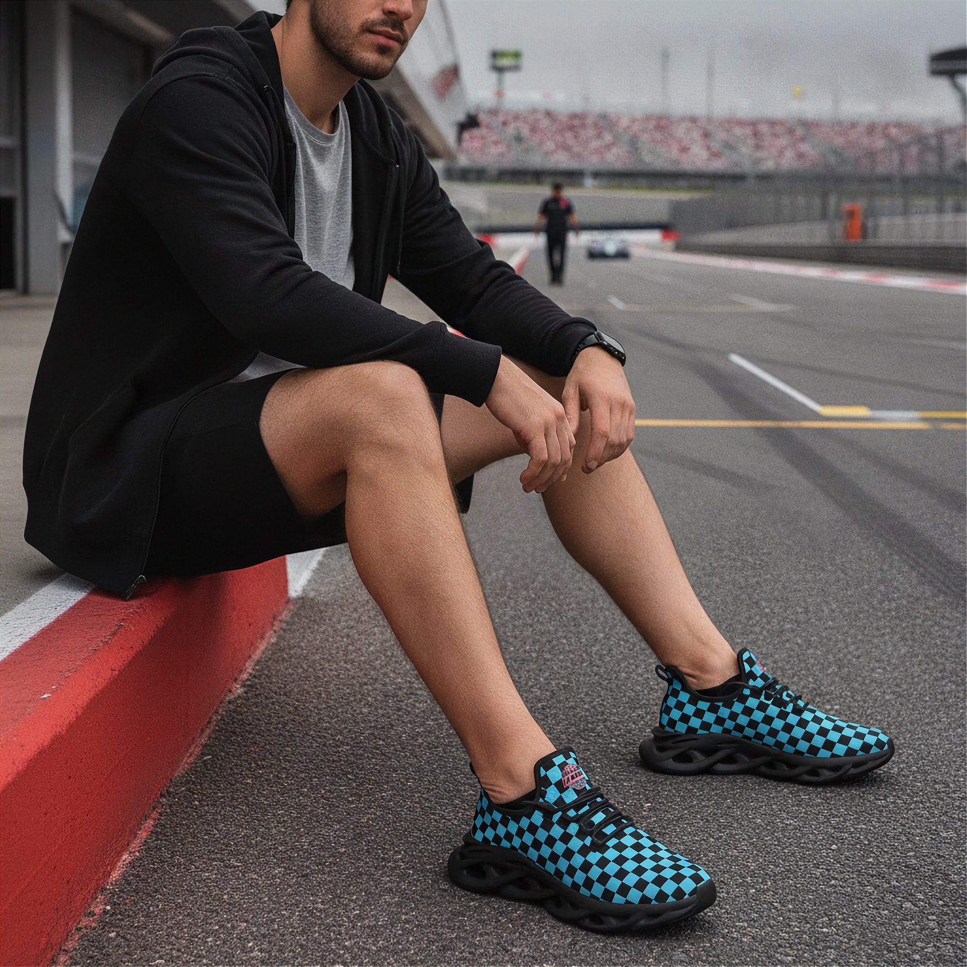Man wearing black and blue checkered shoes sitting on a race track.