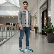 Man standing in a modern indoor setting wearing a gray denim jacket, white shirt, blue jeans, and checkered shoes.