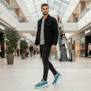 Man walking in a modern shopping mall wearing a black jacket, gray shirt, black jeans, and checkered shoes.