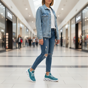 Woman wearing a denim jacket, white shirt, ripped jeans, and checkered shoes in a mall.