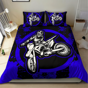 A bed dressed in a motocross-themed bedding set featuring a large black, white, and royal blue graphic of a rider on a dirt bike, with matching pillowcases, shown in a bedroom setting.