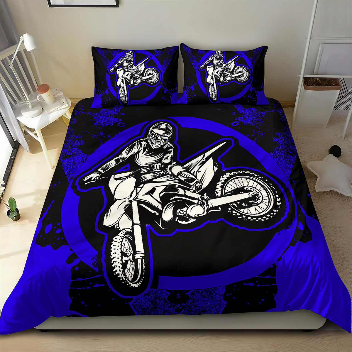 A bed dressed in a motocross-themed bedding set featuring a large black, white, and royal blue graphic of a rider on a dirt bike, with matching pillowcases, shown in a bedroom setting.