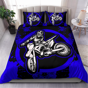 A bed dressed in a motocross-themed bedding set featuring a large black and blue graphic of a rider on a dirt bike, with two matching pillowcases, shown in a styled bedroom setting.