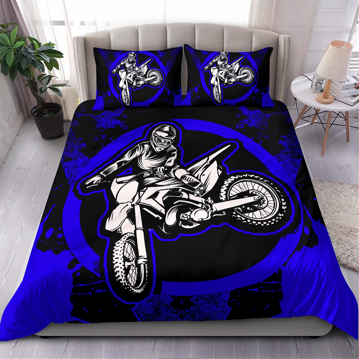A bed dressed in a motocross-themed bedding set featuring a large black and blue graphic of a rider on a dirt bike, with two matching pillowcases, shown in a styled bedroom setting.