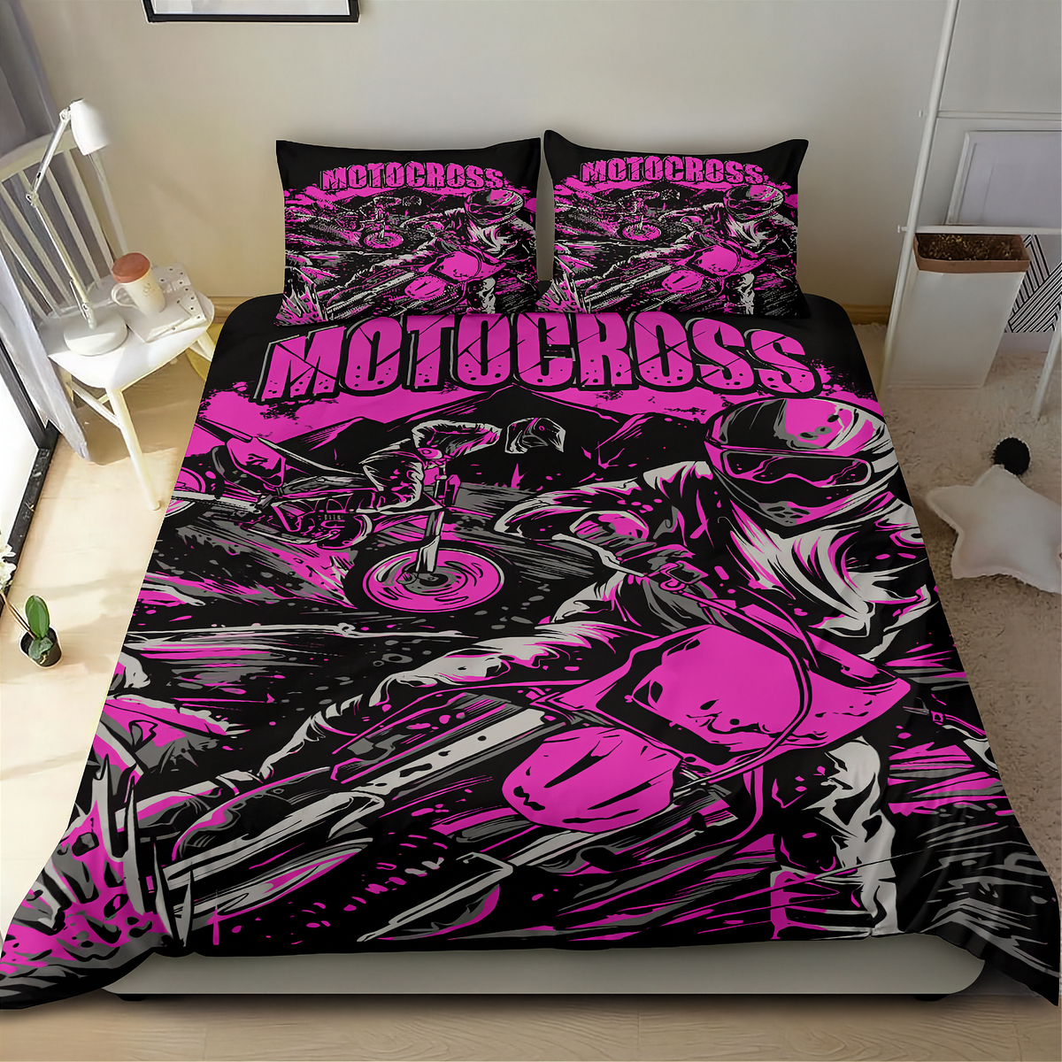 A bed dressed in a motocross-themed bedding set with a bold black, pink, and gray graphic print featuring a motorcycle and rider, shown in a bedroom setting.