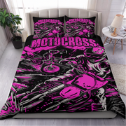 A bed dressed in a motocross-themed bedding set with a bold black, gray, and neon pink graphic print, shown in a styled bedroom setting with two matching pillowcases.
