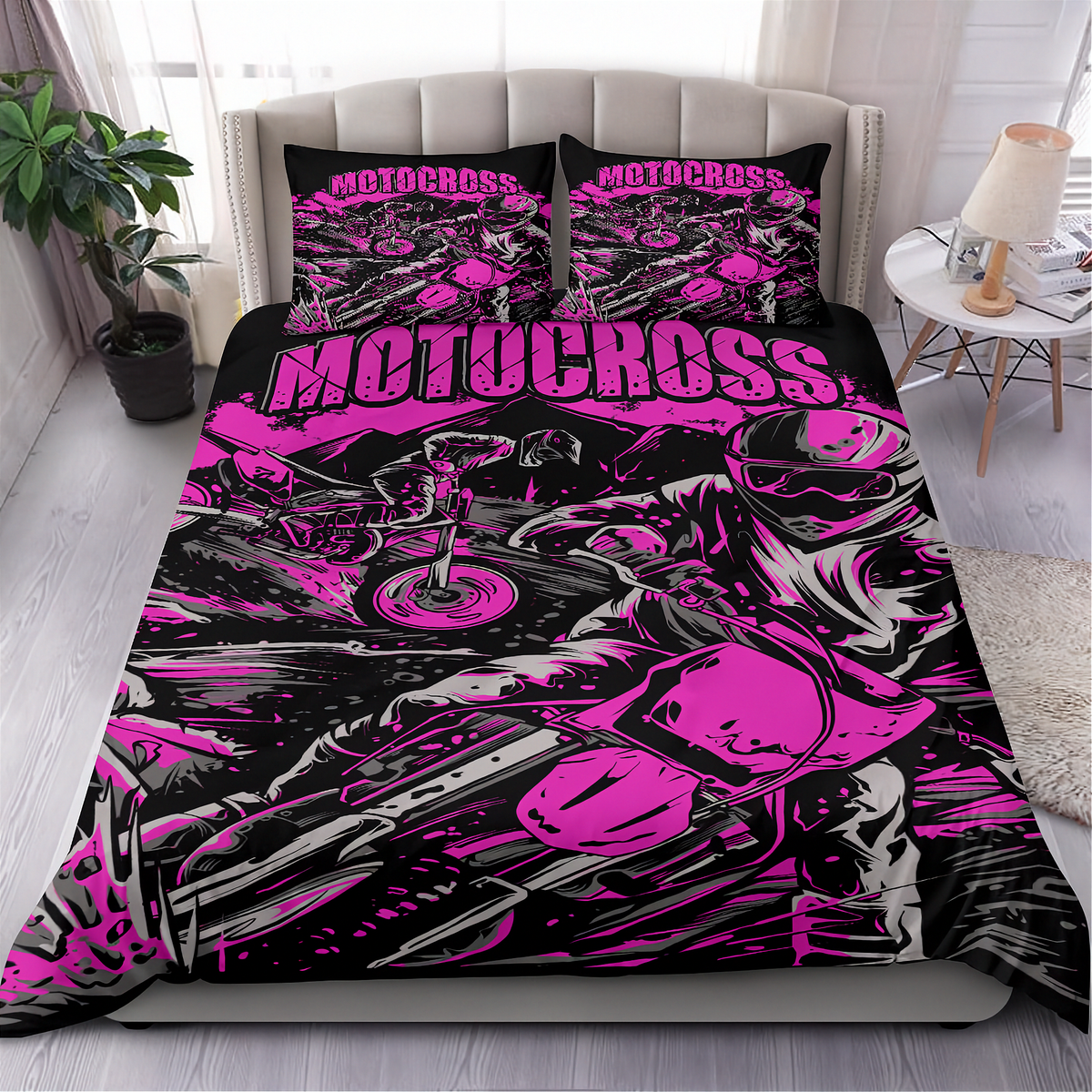 A bed dressed in a motocross-themed bedding set with a bold black, gray, and neon pink graphic print, shown in a styled bedroom setting with two matching pillowcases.
