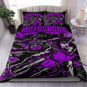 A bed dressed in a motocross-themed bedding set with a large purple and black graphic print featuring a motorcycle and the word 'MOTOCROSS' across the duvet and matching pillowcases, shown in a styled bedroom setting.