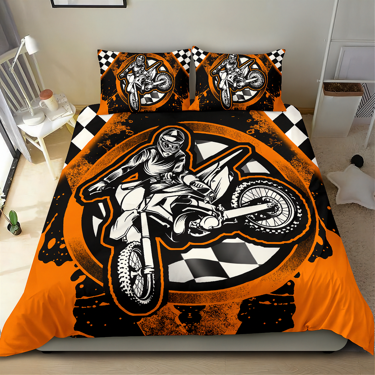 A motocross-themed bedding set featuring a duvet cover and two pillowcases with a bold graphic print of a rider on a dirt bike over a black and orange design with checkered flag patterns, shown on a bed in a bedroom setting.