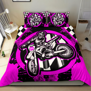 A bed dressed in a motocross-themed bedding set with a duvet cover and two pillowcases, featuring a large black, white, and neon pink graphic of a rider on a dirt bike, with checkered and circular design elements, shown in a bedroom setting.