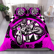 A bed dressed in a motocross-themed bedding set featuring a large black, white, and neon pink graphic of a rider on a dirt bike, with matching pillowcases, shown in a styled bedroom setting.