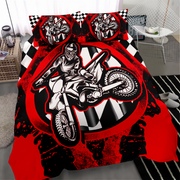 A bed dressed in a bold red, black, and white motocross-themed bedding set, featuring a large graphic of a rider on a dirt bike with checkered and splatter details. Two matching pillowcases are placed on top.