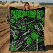 Woman holding a motocross-themed blanket with riders on a dirt track in the background.