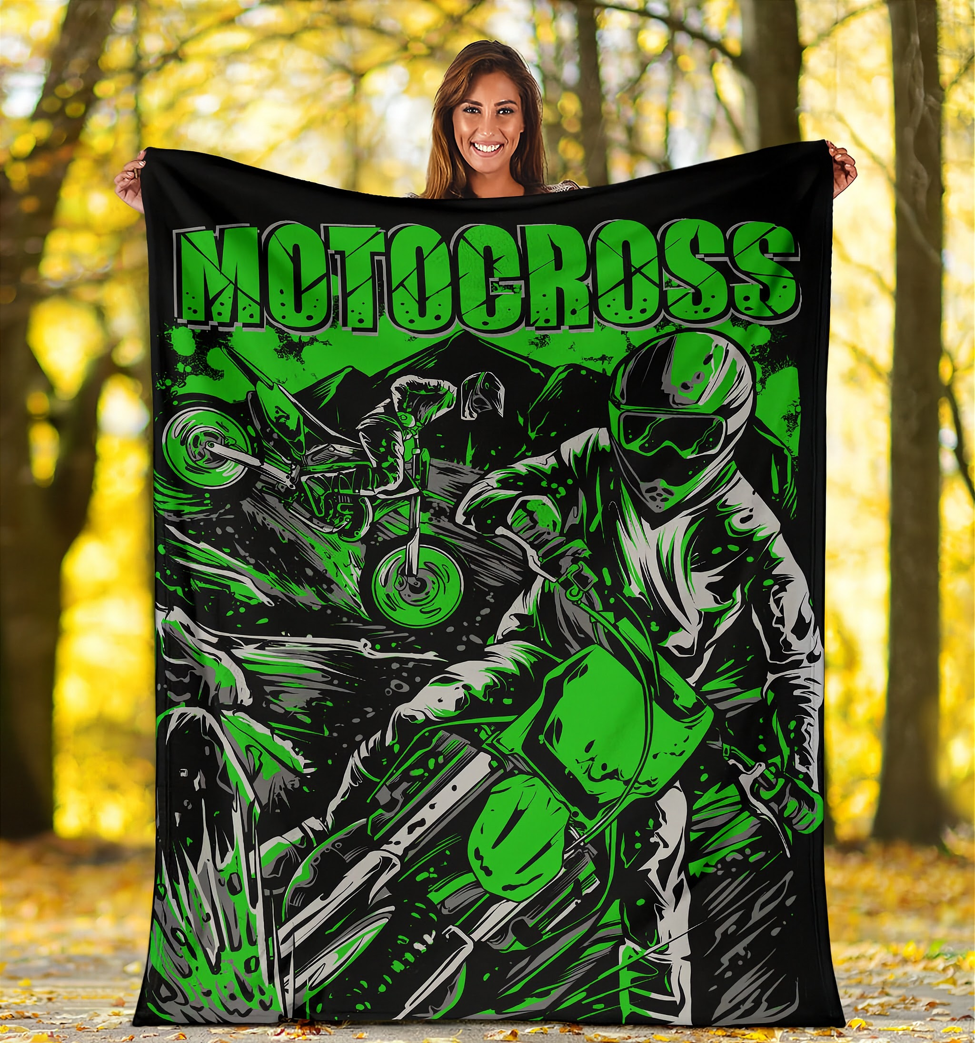 Woman holding a 'Motocross' themed blanket with graphics of a rider and bike in a forest setting.