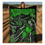 Woman holding a 'Motocross' themed blanket with graphics of a rider and bike on a dirt track background.
